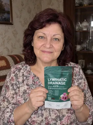Smiling woman with dark red hair holding a pack of Zeelar softgels in her living room