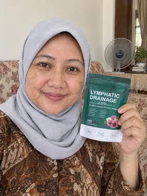 Smiling woman in a headscarf holding a pack of Zeelar softgels in her living room