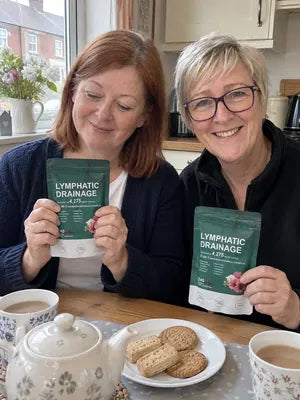 Two friends at a kitchen table, each holding a pack of Zeelar softgels